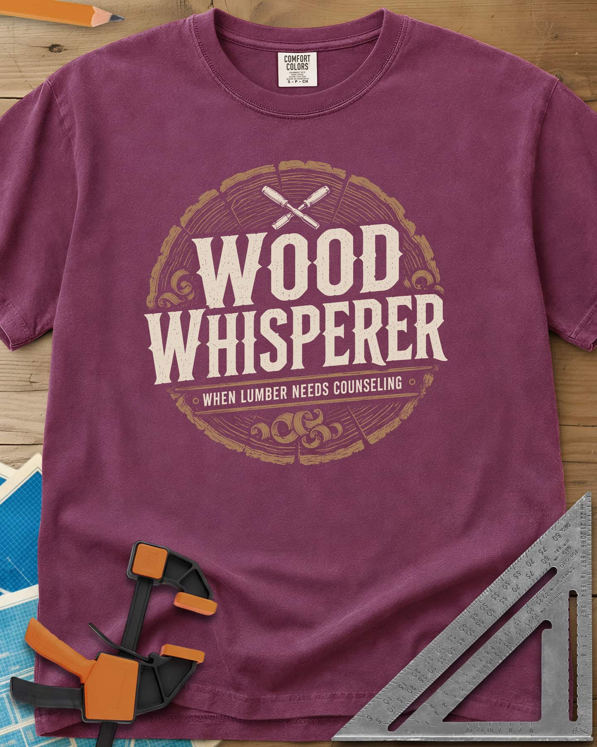 Wood Whisperer heavyweight tee in Berry, a round log-slice badge with crossed chisels and shaving curls