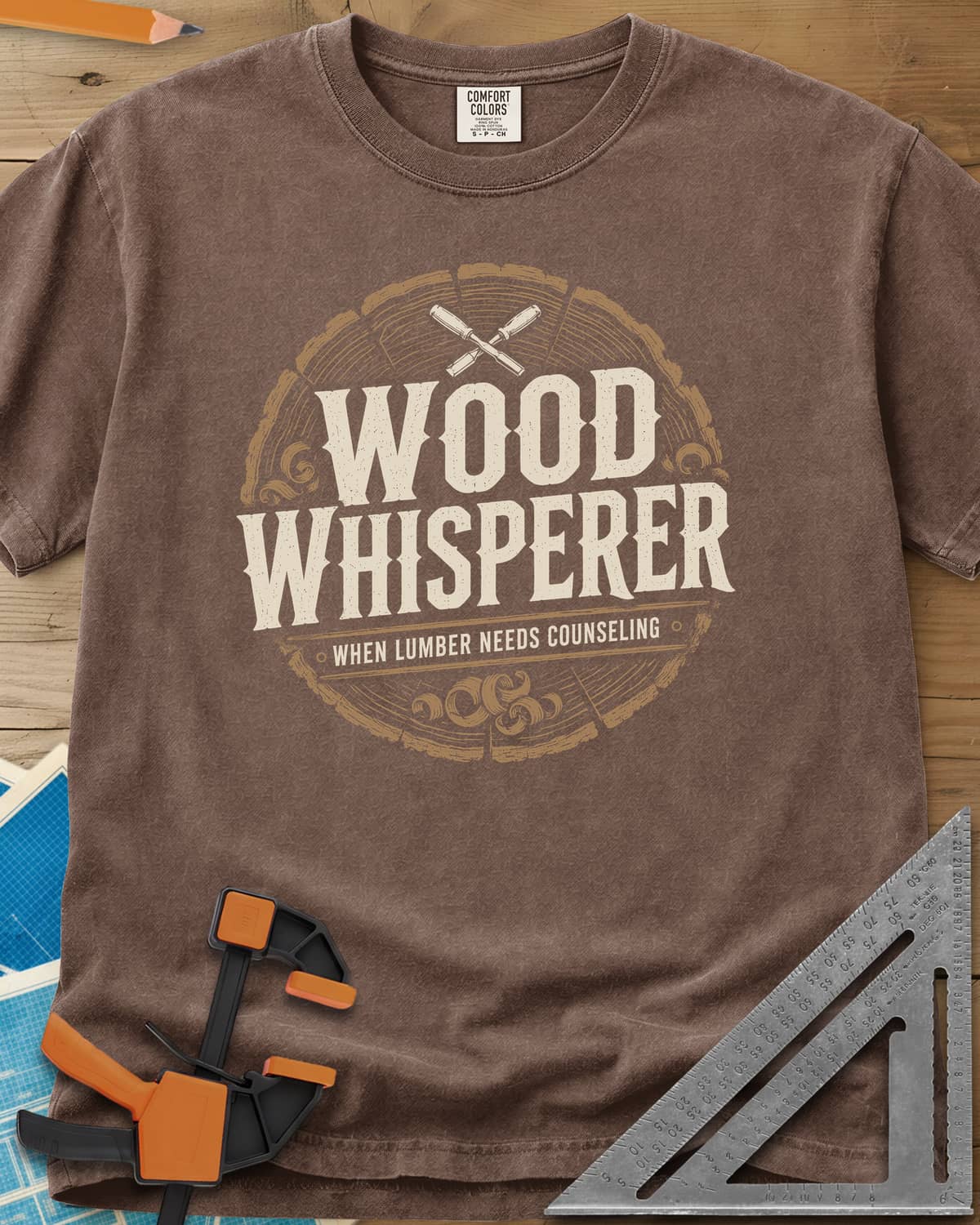 Wood Whisperer heavyweight tee in Espresso, a round log-slice badge with crossed chisels and shaving curls