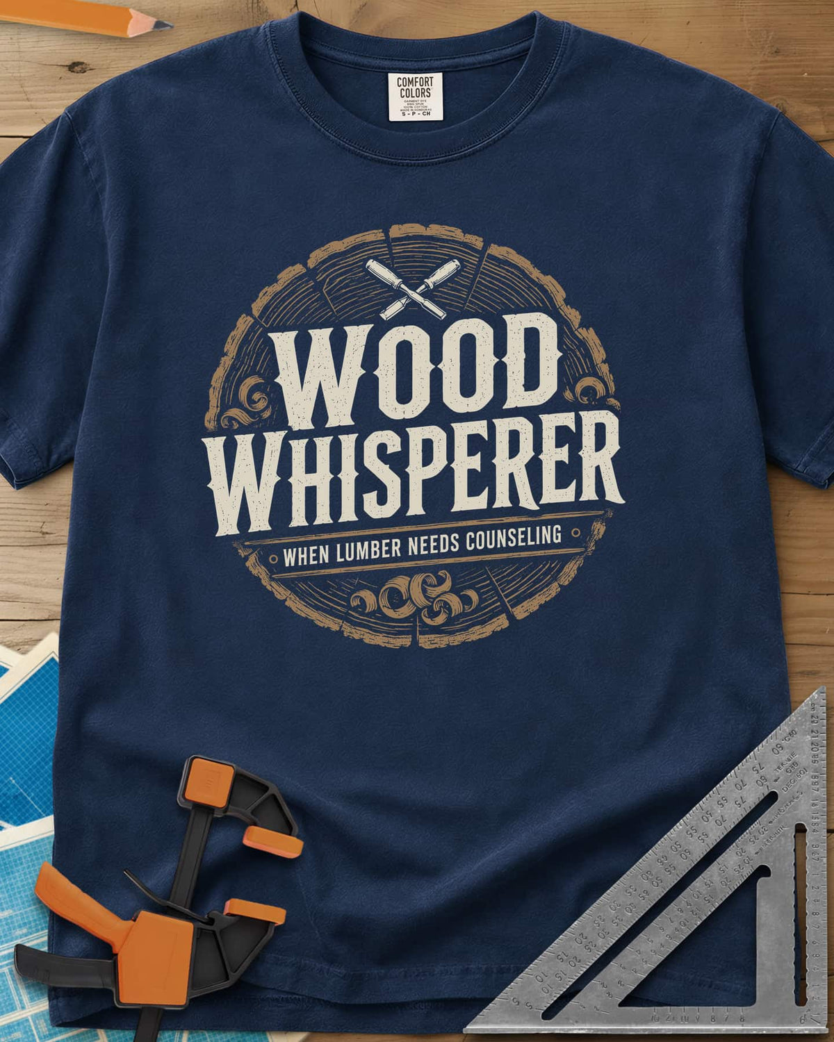 Wood Whisperer heavyweight tee in Navy, a round log-slice badge with crossed chisels and shaving curls