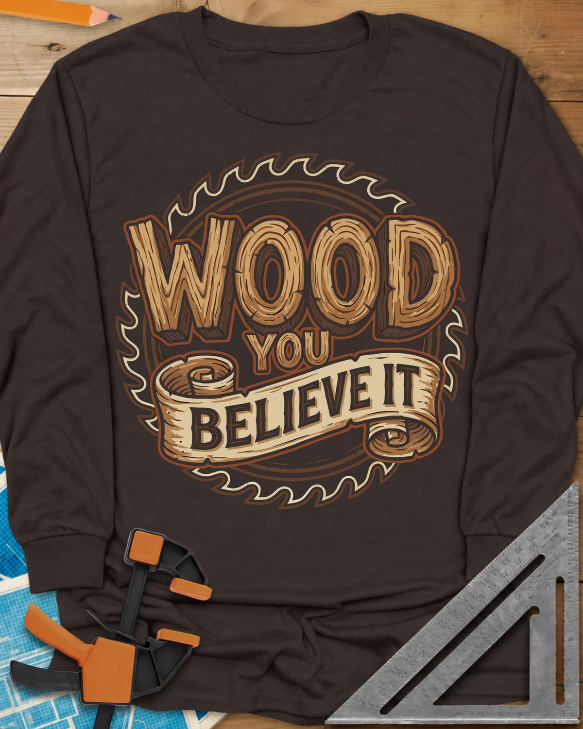 Wood You Believe long sleeve shirt in Dark Chocolate, wood-grain letters on a scroll banner over a circular saw blade