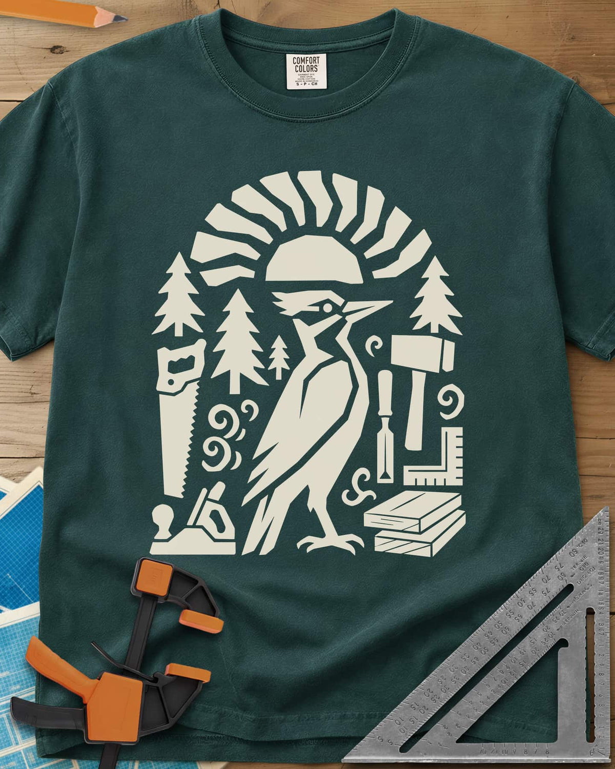 Woodpecker Craft heavyweight tee in Blue Spruce, a geometric woodpecker among saws, planes, chisels and pine trees