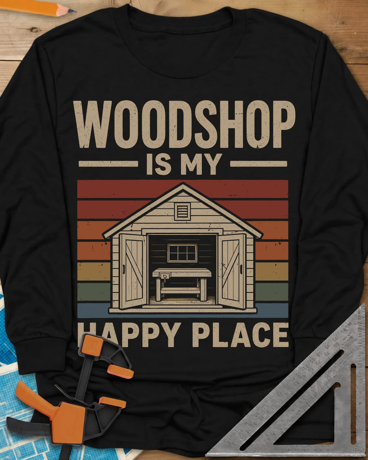 Woodshop Happy Place long sleeve shirt in Black, a small shed with open doors and a workbench on retro sunset stripes