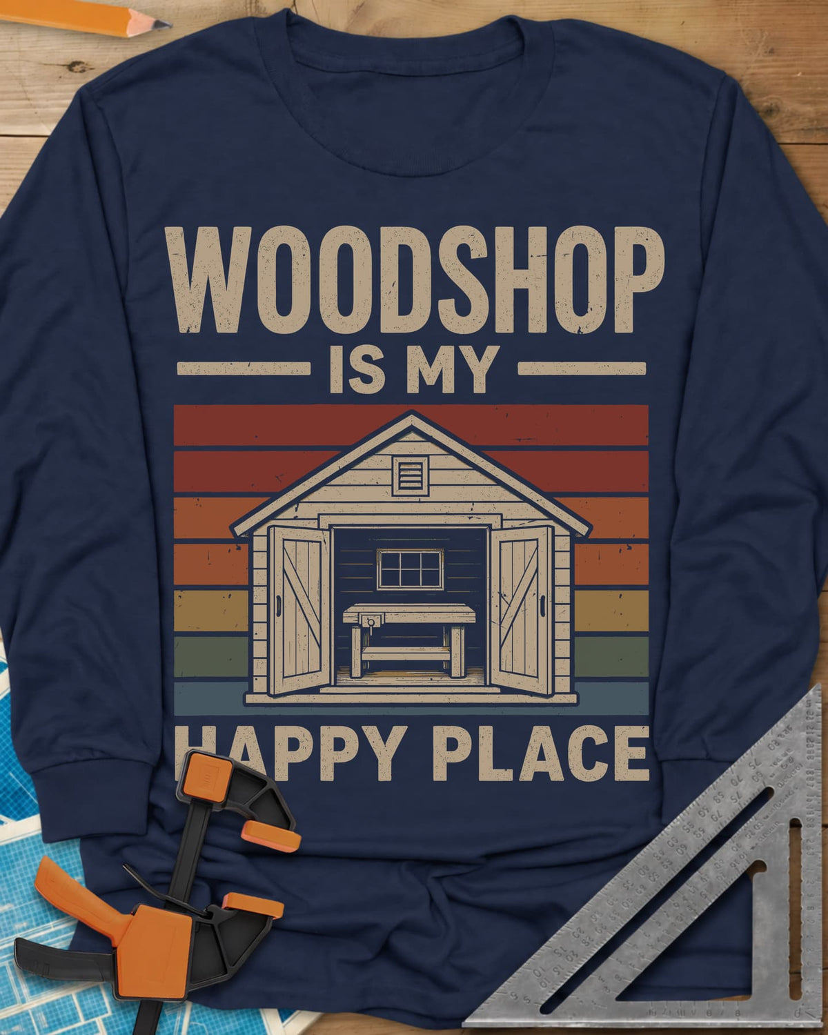 Woodshop Happy Place long sleeve shirt in Navy, a small shed with open doors and a workbench on retro sunset stripes