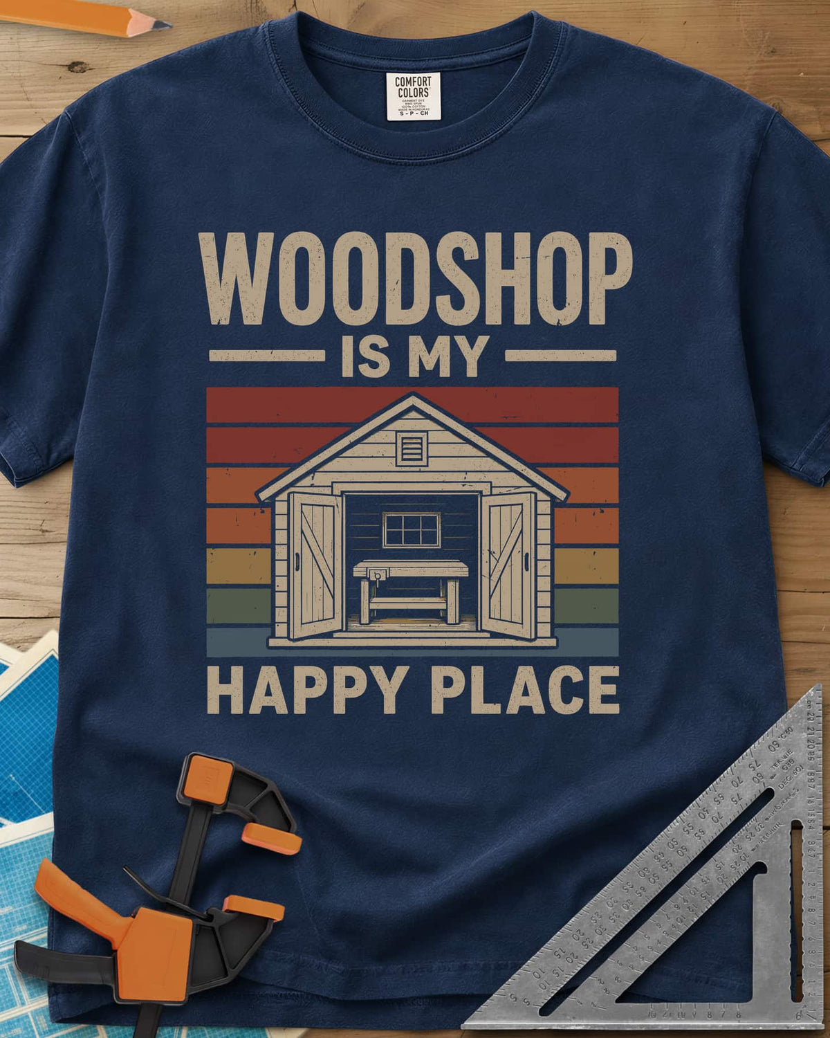 Woodshop Happy Place heavyweight tee in Navy, a small shed with open doors and a workbench on retro sunset stripes