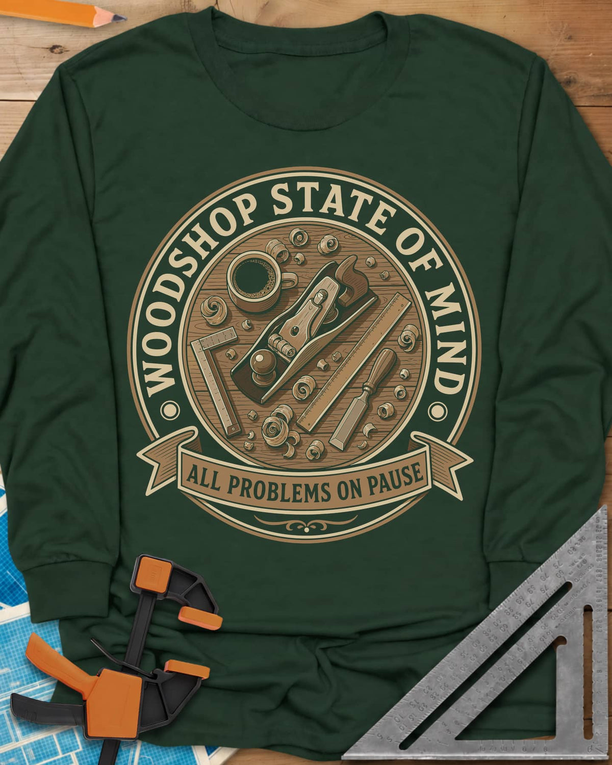 Woodshop State Of Mind long sleeve shirt in Forest Green, a round badge of a hand plane, coffee, chisel and shavings on a