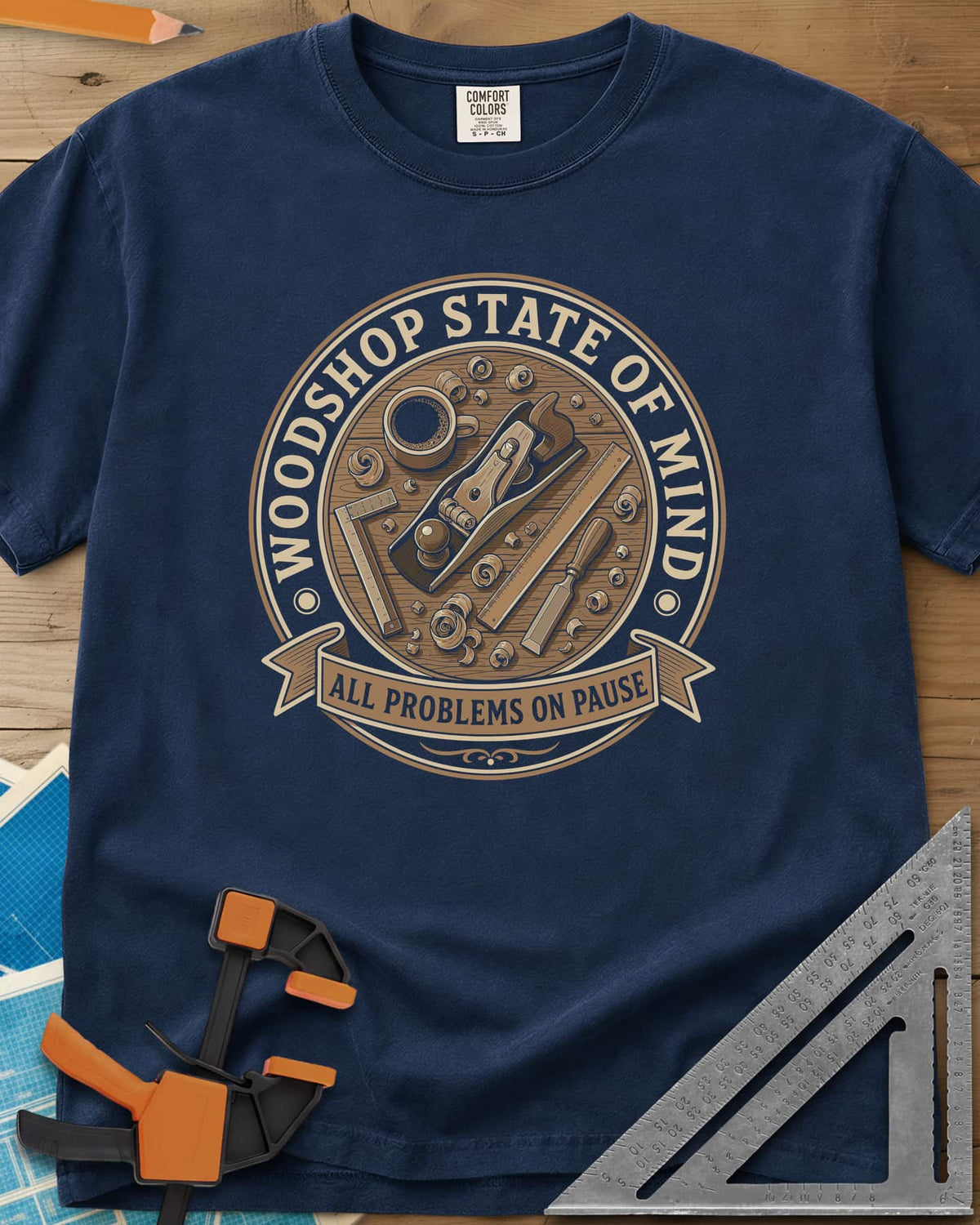 Woodshop State Of Mind heavyweight tee in Navy, a round badge of a hand plane, coffee, chisel and shavings on a bench
