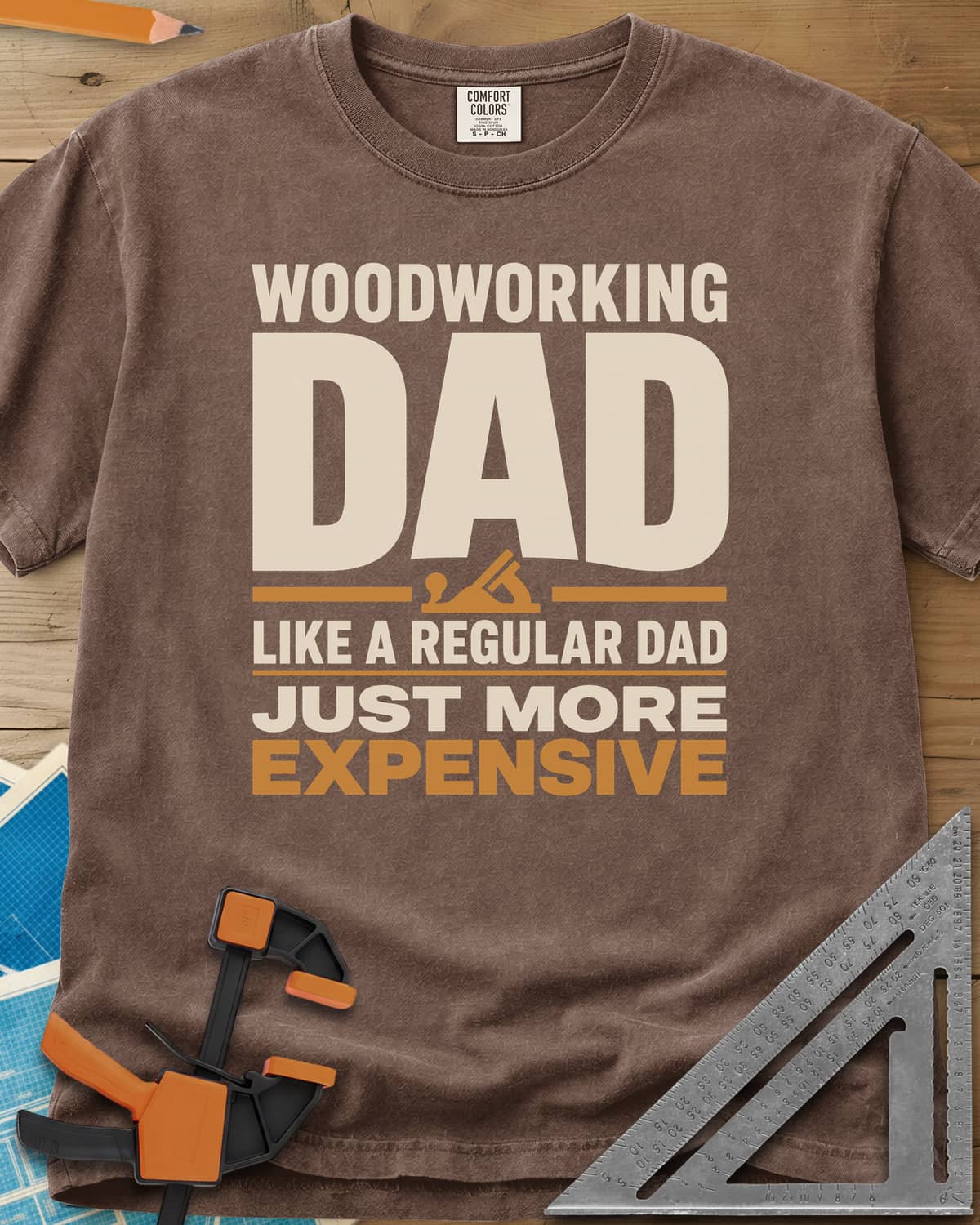 Woodworking Dad Just More Expensive heavyweight tee in Espresso, bold lettering with a small hand plane tucked under DAD