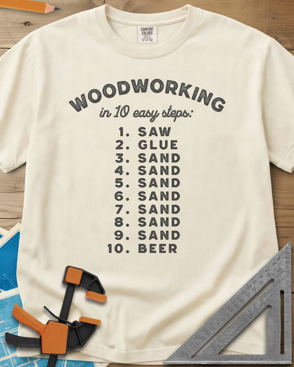 Woodworking in 10 Easy Steps heavyweight tee in Ivory, a numbered list: saw, glue, sand seven times, then beer