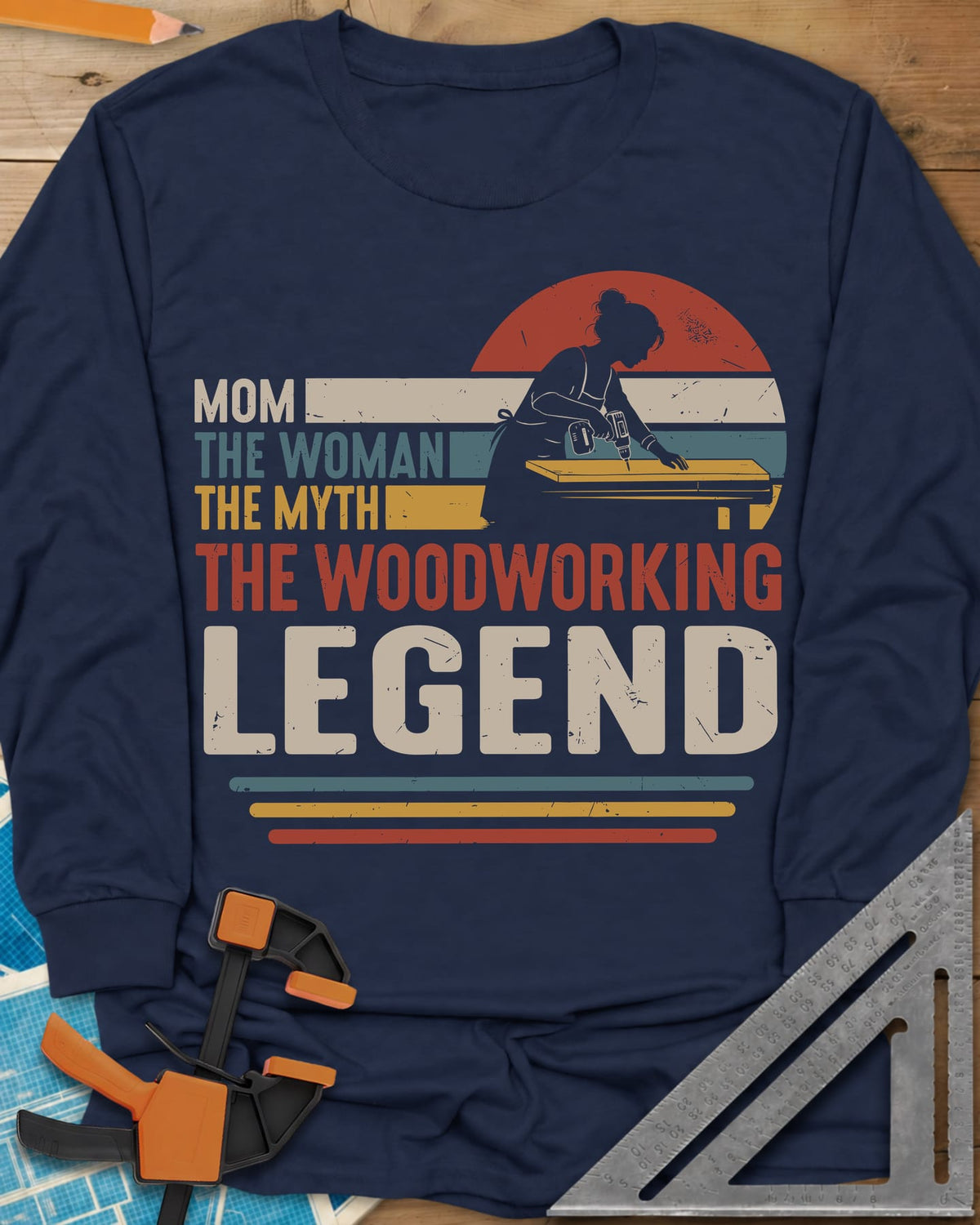 Woodworking Mom Legend long sleeve shirt in Navy, a woman drilling into a board in front of a retro sunset