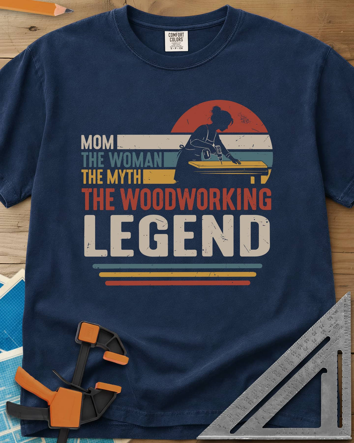 Woodworking Mom Legend heavyweight tee in Navy, a woman drilling into a board in front of a retro sunset