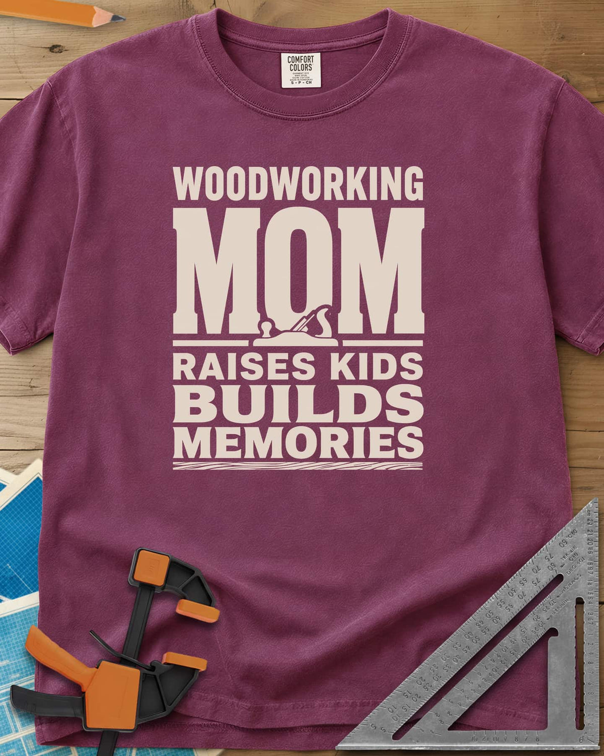Woodworking Mom Memories heavyweight tee in Berry, bold stacked lettering with a hand plane set into the O of MOM