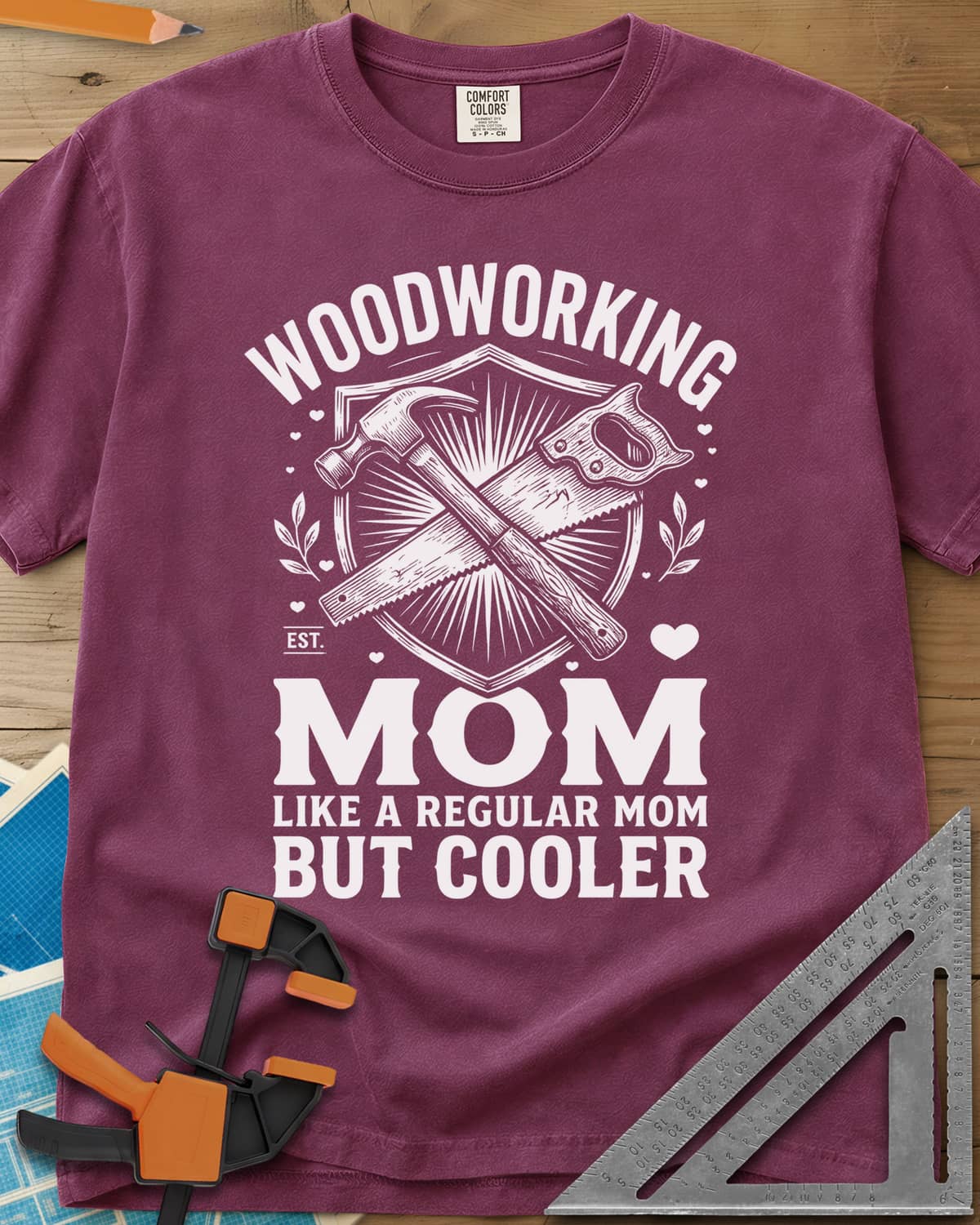 Woodworking Mom heavyweight tee in Berry, a hammer and hand saw crossed on a shield with hearts and leaves
