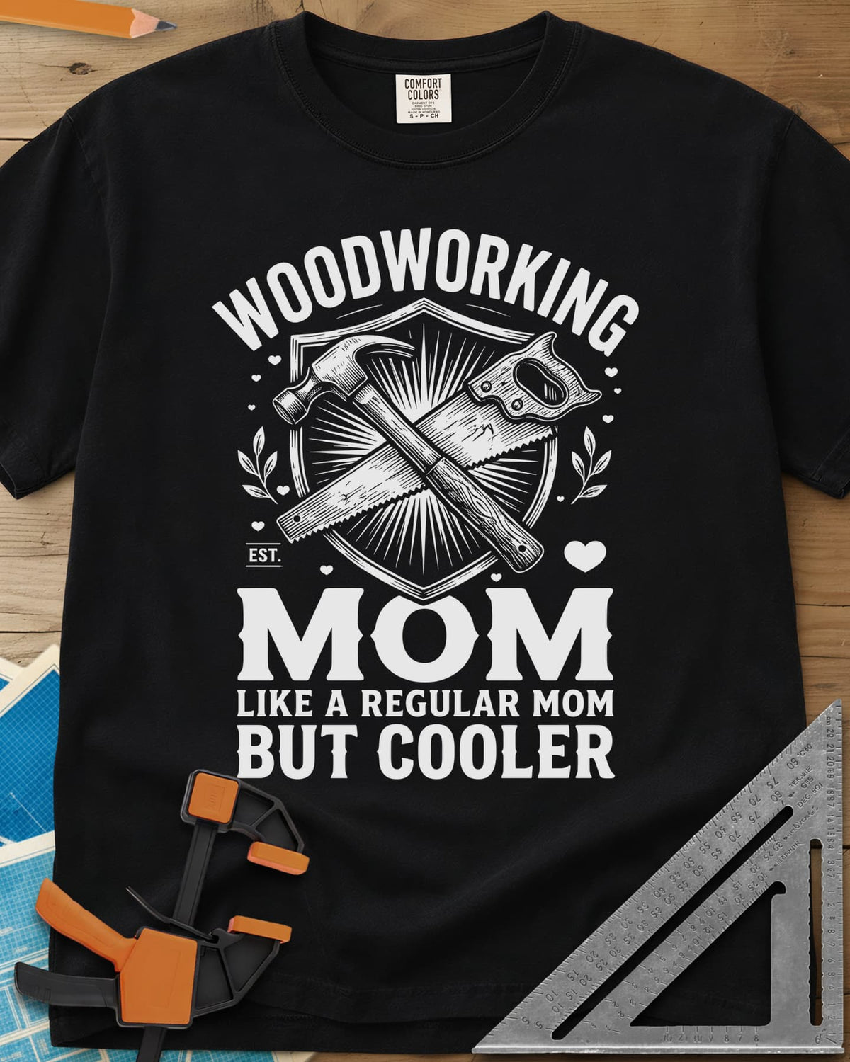 Woodworking Mom heavyweight tee in Black, a hammer and hand saw crossed on a shield with hearts and leaves