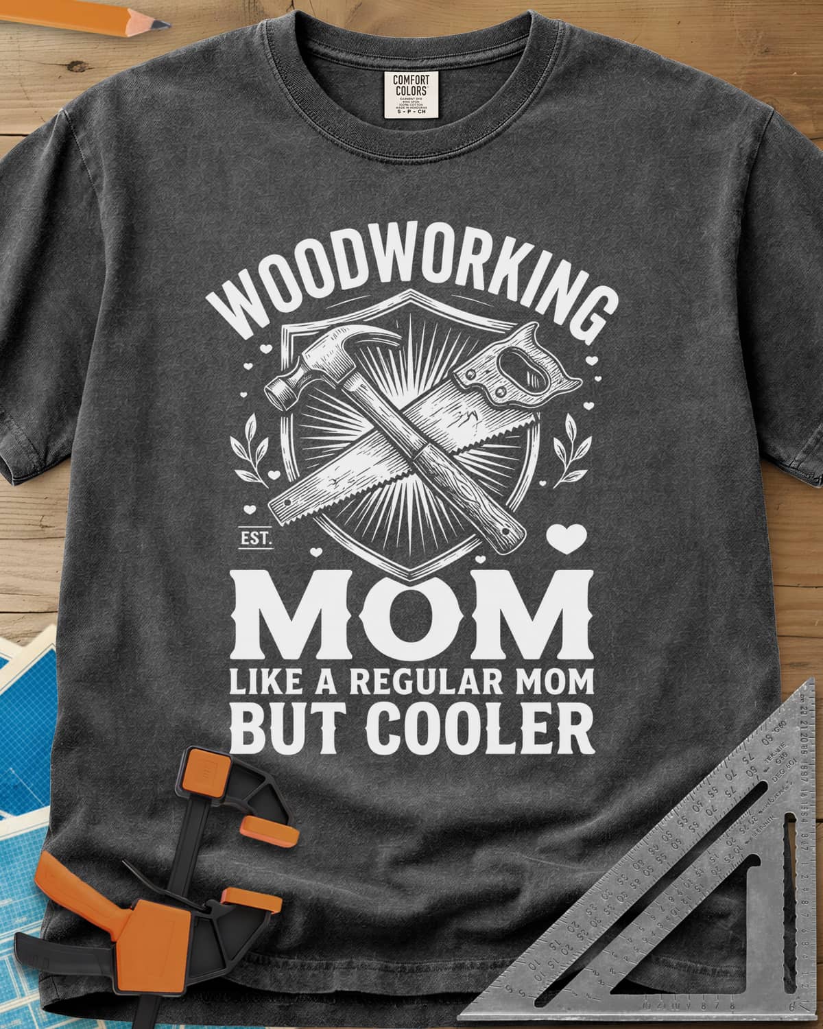 Woodworking Mom heavyweight tee in Pepper, a hammer and hand saw crossed on a shield with hearts and leaves