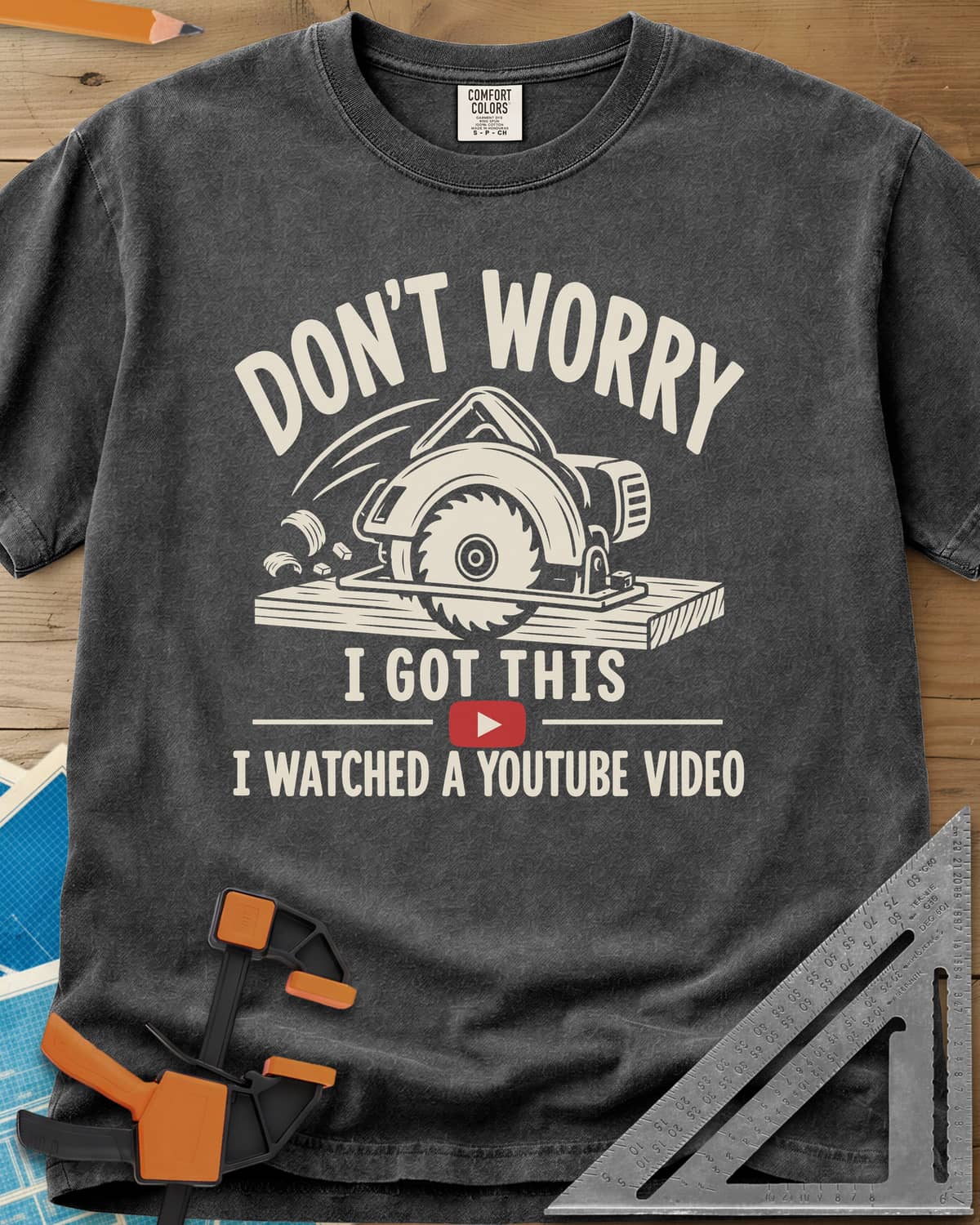 YouTube Pro heavyweight tee in Pepper, a circular saw cutting a plank with flying chips and a red play button