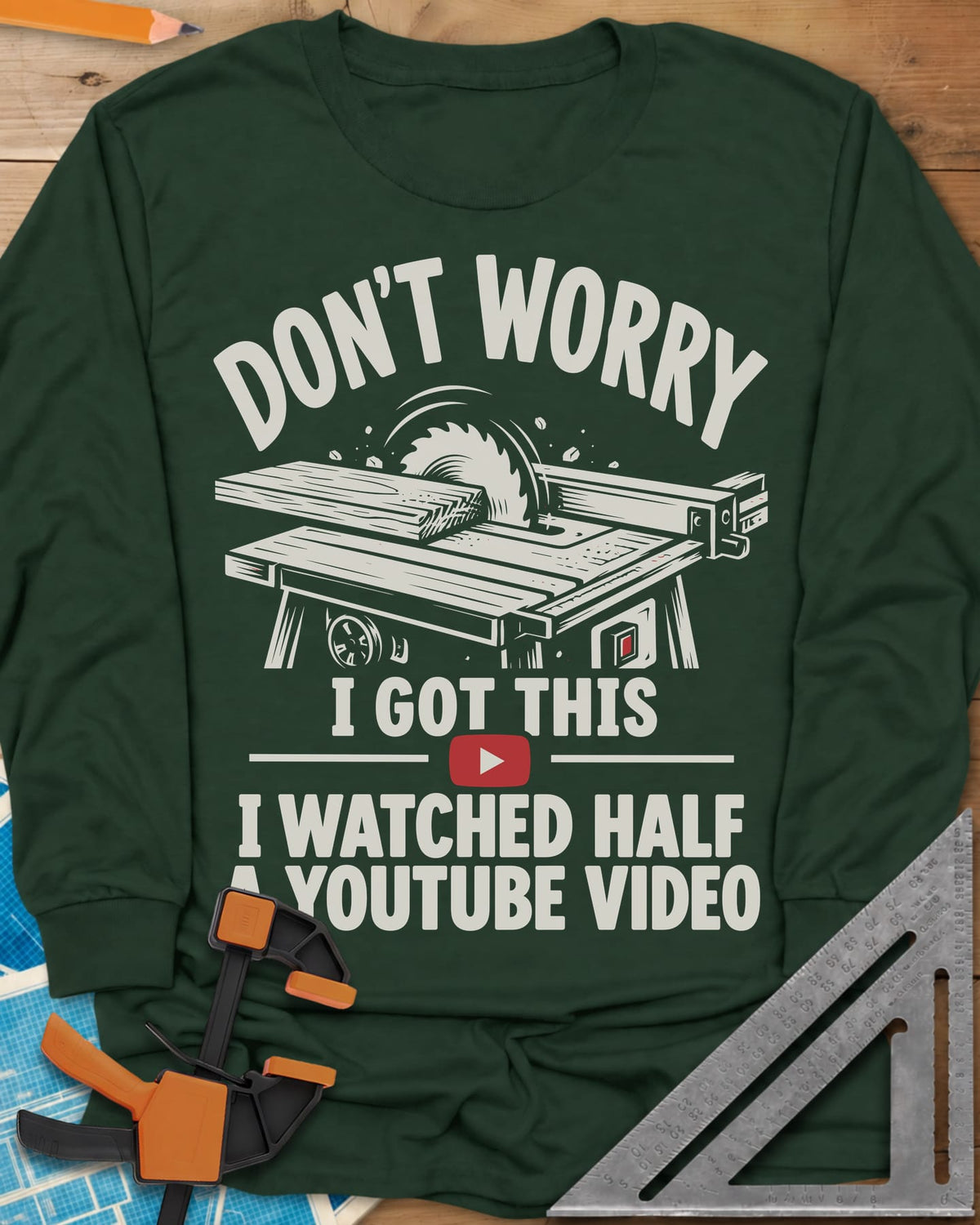 YouTube Video long sleeve shirt in Forest Green, a table saw with a board at the blade above a red play button